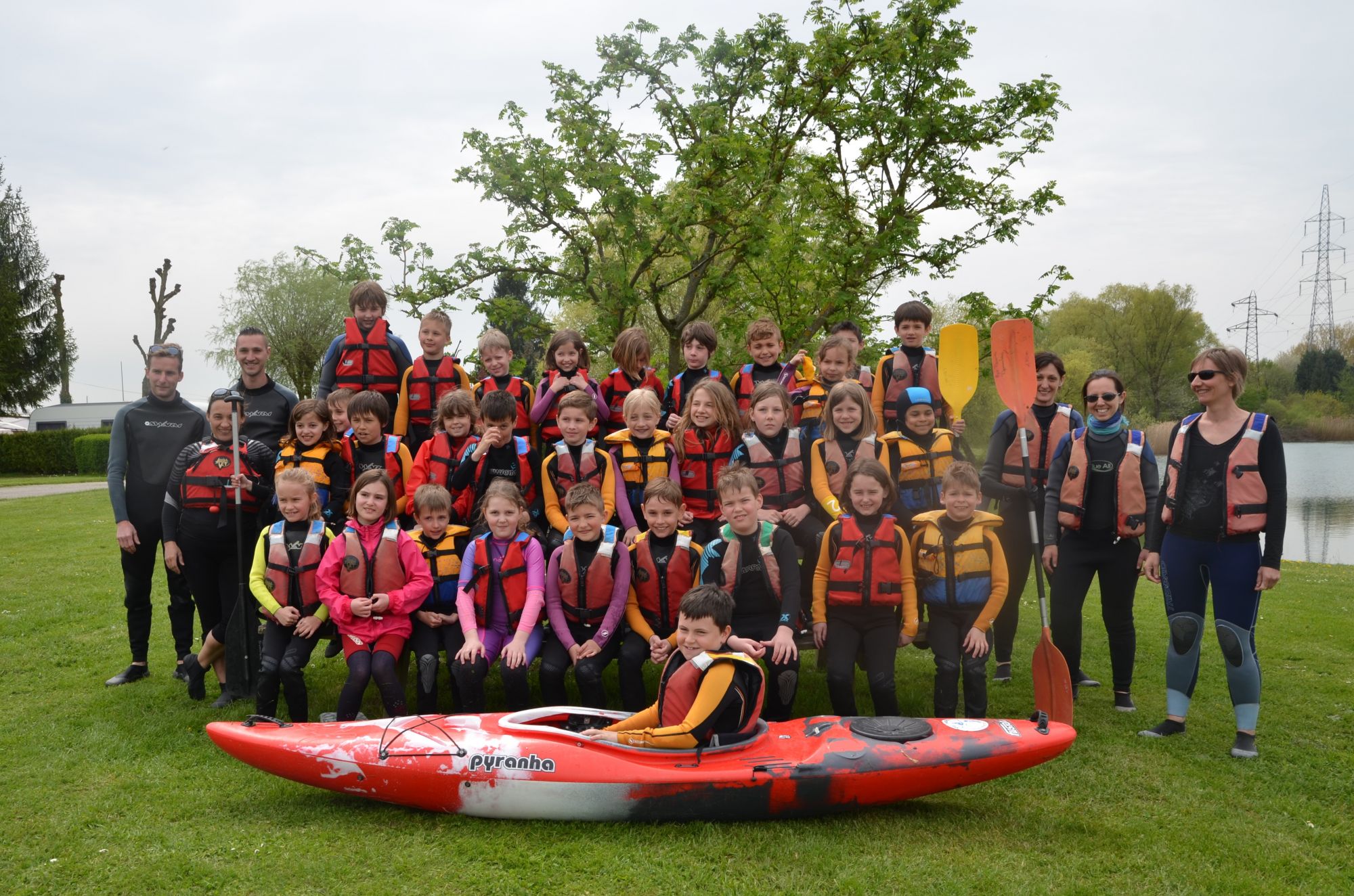 Groupe d'enfants en tenue de canoé pose devant un canoë kayak 